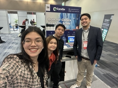 CareGo Health Suite team posing together at their event booth, with a banner reading 'Built for Clinics Ready to Scale' behind them.