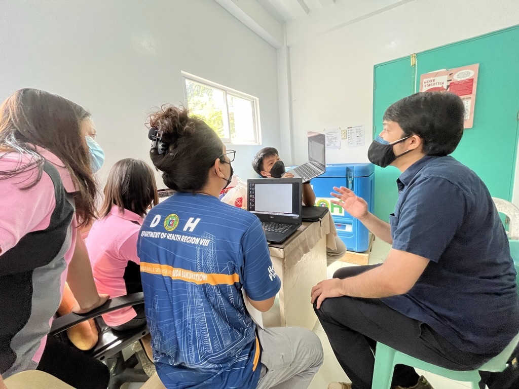 CareGo team discussing the CareGo system with Department of Health Region VIII staff during a field visit, with laptops set up nearby for a hands-on session.